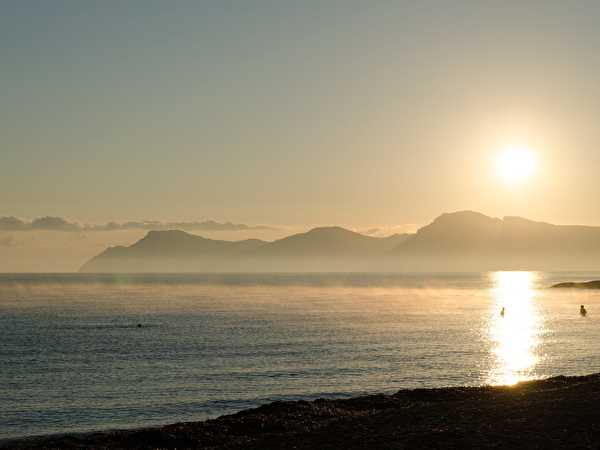 Sonnenuntergang am Meer mit Bergen im Hintergrund